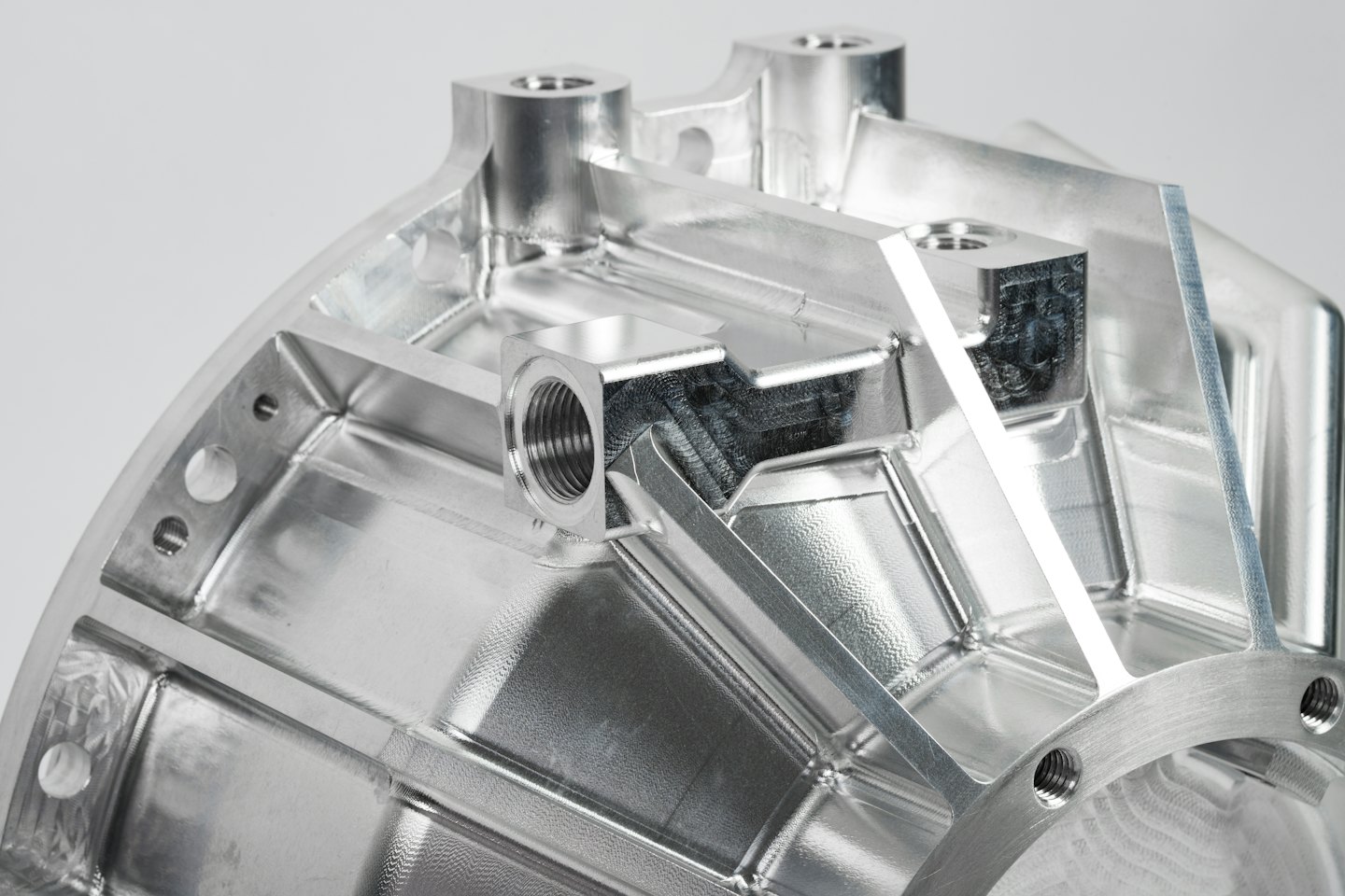 A complex machined silver component with detailed threads and textures.