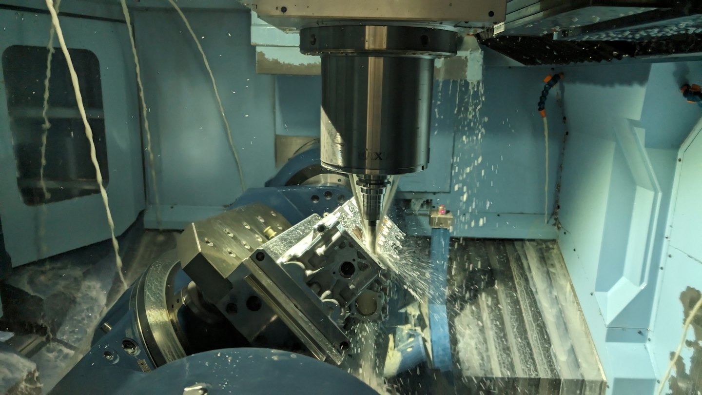 CNC milling machine sprays coolant onto metal workpiece.