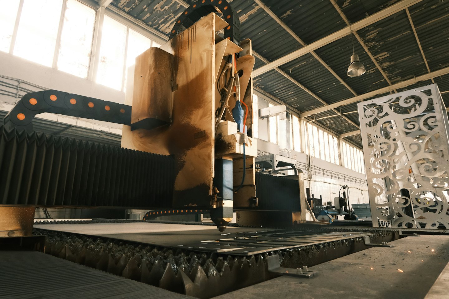 Industrial laser cutter shaping metal sheet in a factory.