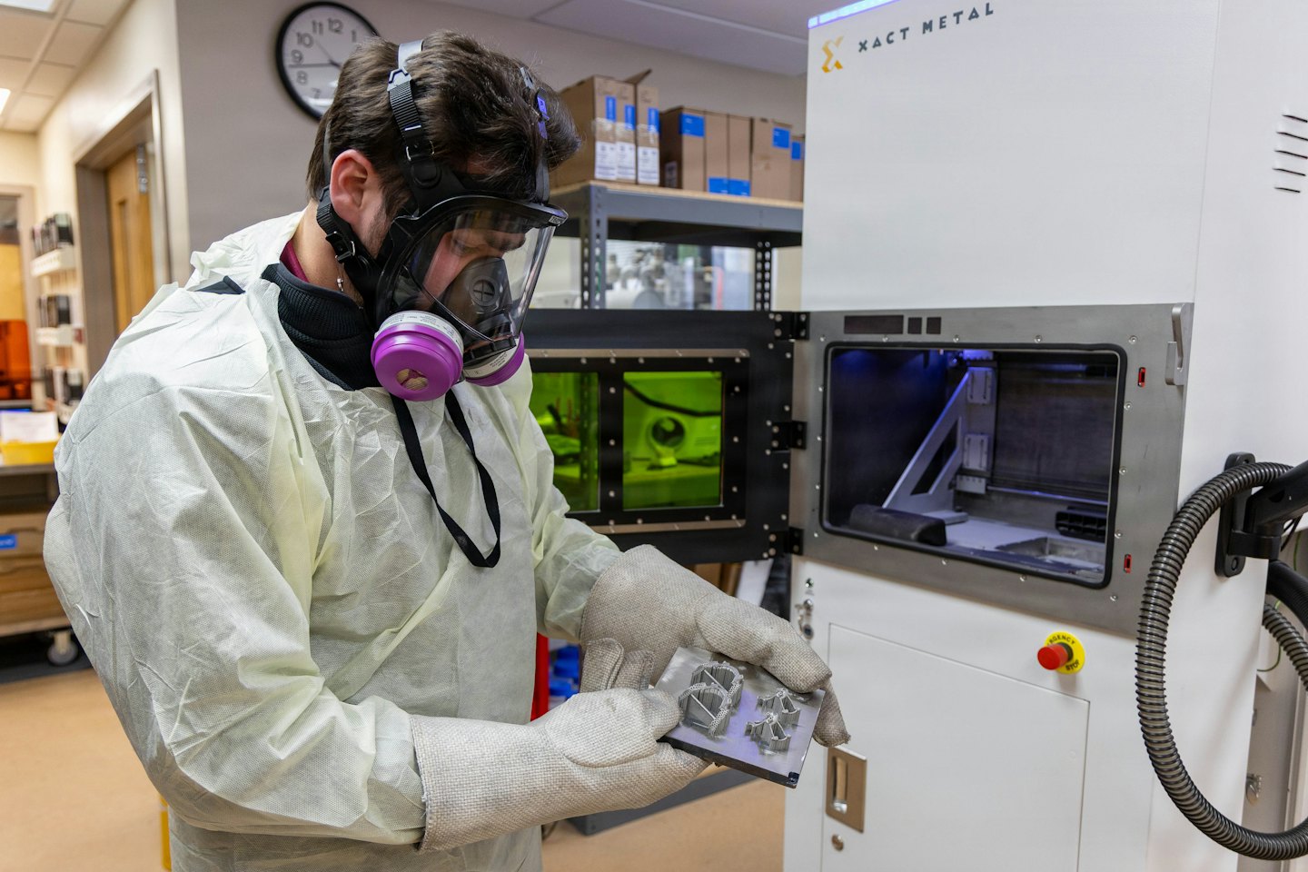 Technician inspects 3D printed metal parts in a lab.